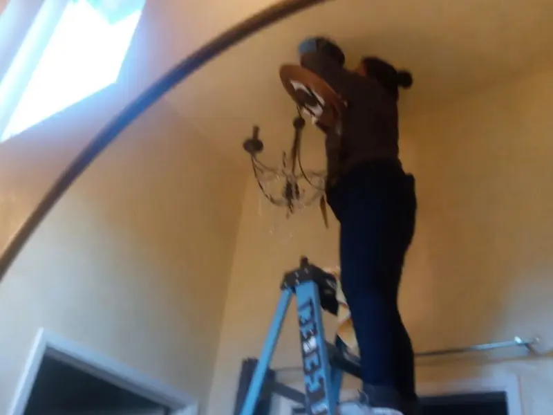 Electrician installing a chandelier in a Kenner residence